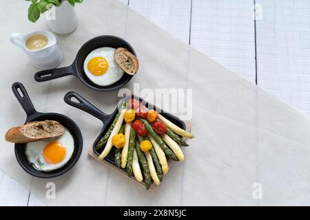 Asparagi verdi e bianchi serviti con pomodori, uova fritte, patate bollite. Questo piatto di stagione è molto popolare in Germania durante lo Spargelzeit Foto Stock