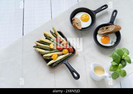 Asparagi verdi e bianchi serviti con pomodori, uova fritte, patate bollite. Questo piatto di stagione è molto popolare in Germania durante lo Spargelzeit Foto Stock