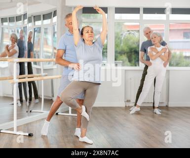 Felice coppia di ballerini maturi che eseguono coreografie con supporto durante i corsi di formazione di gruppo in studio di danza Foto Stock