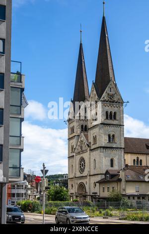 Olten, Svizzera - 25 maggio 2024: Storica chiesa cittadina di San Martin , edifici moderni nelle vicinanze, ambiente urbano con auto Foto Stock