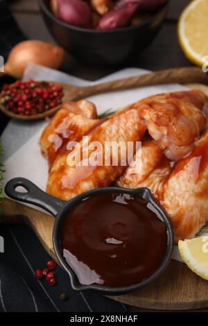 Marinata fresca e ali di pollo crude sul tavolo, primo piano Foto Stock