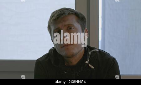 Primo piano di un uomo con un'espressione interessata guarda la fotocamera. Stock. L'uomo inclina la testa con interesse e guarda la telecamera. Espressioni facciali interessanti Foto Stock