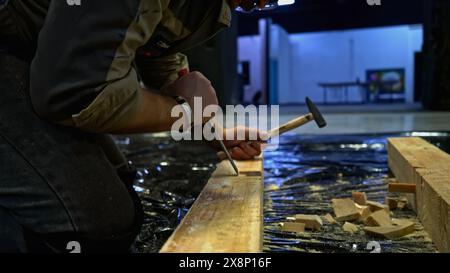 Primo piano del lavoratore che utilizza gli attrezzi per realizzare fori in travi di legno. Supporto. Lavori di falegnameria per la realizzazione di decorazioni. Foto Stock