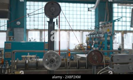 Macchina industriale con bobine rotanti e filo. Creatività. Avvolgimento industriale di fili e cavi su macchine utensili. Macchine automatizzate con bobine Foto Stock