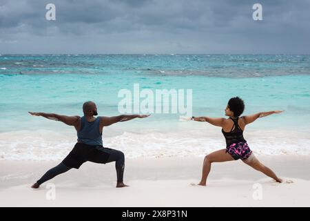 Potente coppia afroamericana che fa yoga sulla spiaggia delle Isole Abaco. Foto Stock