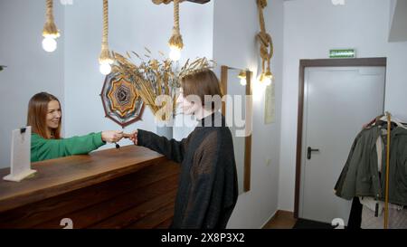 Il giovane effettua il check-in in un hotel. Supporto. Il receptionist felice dà la chiave a un uomo al banco della reception, concetto di viaggio. Foto Stock