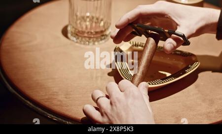 Primo piano di un uomo che taglia il sigaro. Supporto. L'uomo taglia il bordo del Viagra per fumare. Coltello da taglio sigaro professionale nel club cubano Foto Stock