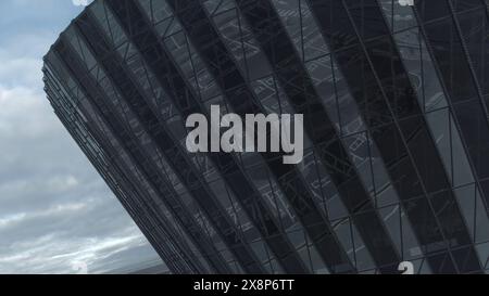 Facciata di un edificio circolare in vetro con riflessi. Riproduci filmati. Vista dall'alto dell'edificio in vetro con riflesso della città. Facciata in vetro di affari moderni Foto Stock