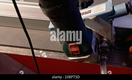 Il processo di taglio di lastre in gres porcellanato con una fresa idraulica. Creatività. Preparazione di piastrelle per la posa su pareti o pavimenti. Foto Stock