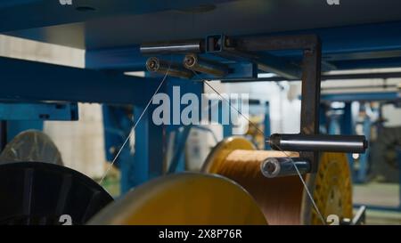 Bobine rotanti con fili in fabbrica. Creatività. Distribuzione e avvolgimento di fili su bobine presso le imprese metallurgiche. Avvolgimento delle linee polimeriche su Foto Stock