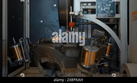 Macchina automatizzata con bobine rotanti e filo. Creatività. Le bobine ruotano sulla pila con il filo di avvolgimento. La macchina industriale ruota e avvolge il filo di rame Foto Stock