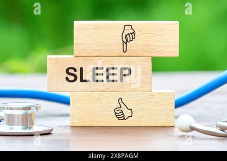 Simbolo sonno profondo. La parola "SONNO" è scritta su barre di legno accanto allo stetoscopio Foto Stock