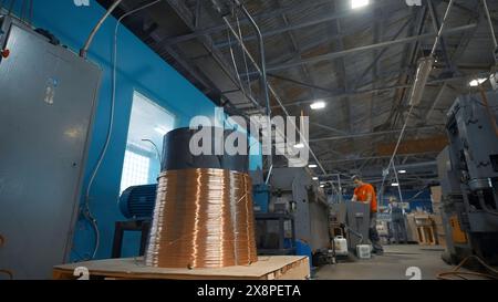 Filo di rame su bobina industriale con funzionamento. Creatività. Il lavoratore regola il funzionamento delle macchine industriali sul pannello di controllo. Impostazioni industriali di Foto Stock