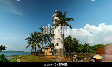 Faro di Galle presso Galle Fort, Sri Lanka. Azione. Bellissime palme e cielo nuvoloso blu. Foto Stock