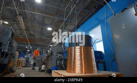 Filo di rame su bobina industriale con funzionamento. Creatività. Il lavoratore regola il funzionamento delle macchine industriali sul pannello di controllo. Impostazioni industriali di Foto Stock