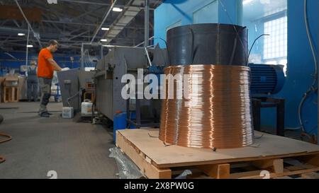 Filo di rame su bobina industriale con funzionamento. Creatività. Il lavoratore regola il funzionamento delle macchine industriali sul pannello di controllo. Impostazioni industriali di Foto Stock