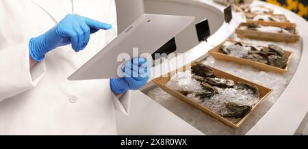 Specialista del controllo della qualità alimentare che esamina le ostriche nei supermercati, primo piano. Design banner Foto Stock