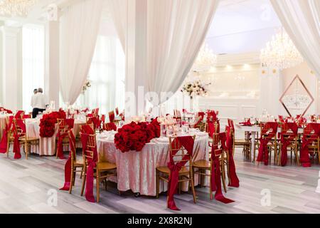 Ricevimento di nozze con decorazioni in rosso e oro e centrotavola floreale Foto Stock