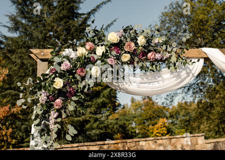 Arco nuziale in legno decorato con motivi floreali e tendaggi, allestito all'aperto Foto Stock