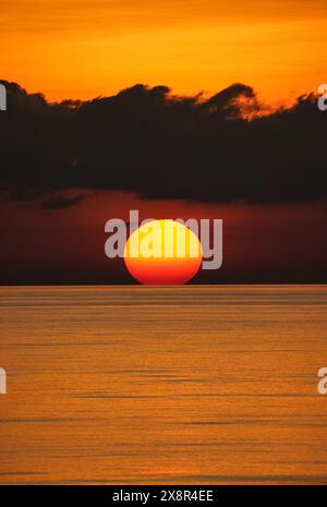 Haikou. 24 marzo 2023. Questa foto scattata il 24 marzo 2023 mostra una vista del tramonto nel Mar Cinese meridionale. Il mare calmo, le nuvole colorate, il cielo stellato notturno, la magnifica alba e il tramonto si svolgono lentamente come un rotolo di immagini nel Mar Cinese meridionale. Crediti: Ding Yongchang/Xinhua/Alamy Live News Foto Stock