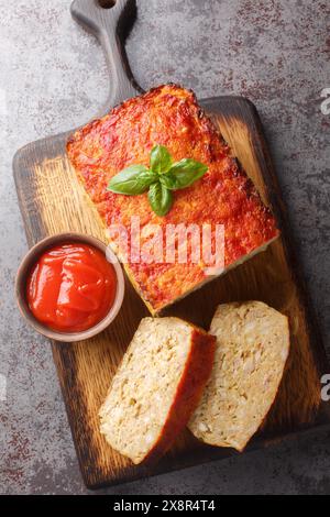 Polpettone o terrina fatti in casa con un mix di pollo e tacchino glassato con ketchup primo piano sul tavolo. Vista verticale dall'alto da Foto Stock