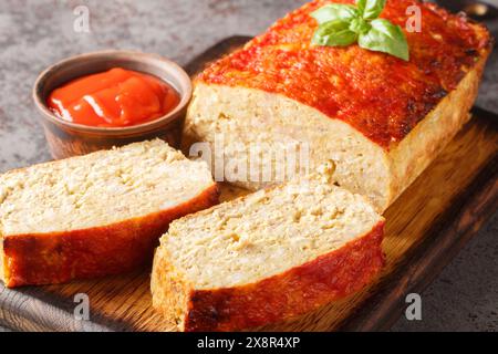 Polpettone con tritatutto di pollo, cipolla e aglio glassati con ketchup primo piano sul bordo di legno sul tavolo. Orizzontale Foto Stock