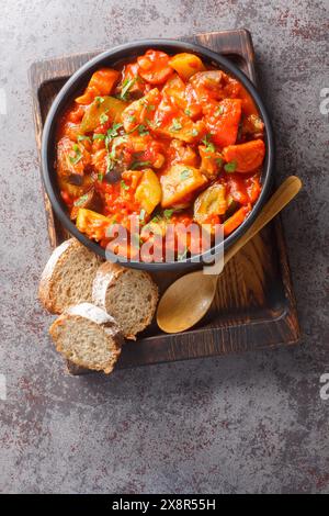 Stufato di verdure di zucchine, peperoni, cipolle, pomodori e melanzane da vicino in un recipiente sul tavolo. Vista dall'alto verticale Foto Stock