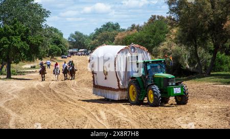 Gruppo di pellegrini che compiono la parte finale del pellegrinaggio di El Rocio in grandi vagoni letto trainati da trattori lungo le strade sabbiose Foto Stock