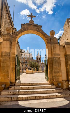 La vista panoramica attraverso un passaggio ad arco medievale rivela l'iconica Cappella di Santa Maria Maddalena nel nucleo storico di Pjazza San Pawl Rabat. heritag culturale Foto Stock