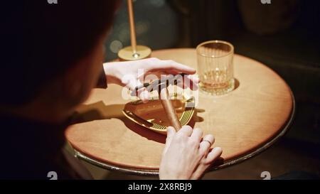 Uomo che taglia il sigaro. Supporto. L'uomo taglia la testa del sigaro per fumare. L'uomo taglia il sigaro professionalmente nel ristorante Foto Stock