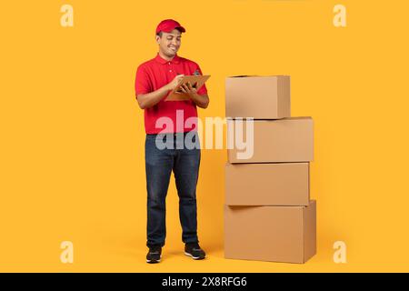 Addetto alla consegna che controlla l'inventario dei pacchetti su sfondo giallo Foto Stock