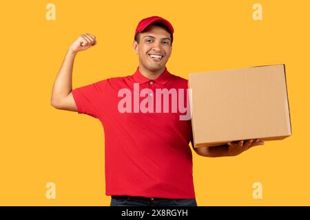 Consegna in attesa di un pacco sorridente per il lavoratore su sfondo giallo durante il giorno Foto Stock