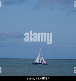 Gommone a vela che partecipa a una regata nello stretto di Menai al largo della costa di Beaumaris ad Anglesey, nel Galles del Nord. Foto Stock