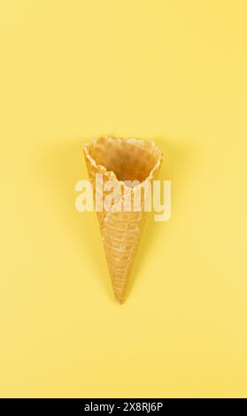 Vista dall'alto del cono di gelato per waffle su sfondo giallo. Carta da parati estiva, piano, spazio per copie. Foto Stock