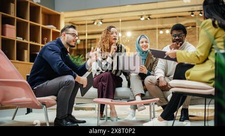 Un gruppo multietnico di persone che discutono idee in una sala riunioni dell'ufficio. Uomini d'affari che prendono decisioni creative per l'avvio e discutono delle opzioni Foto Stock