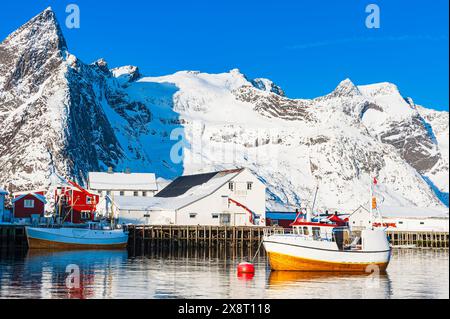 La barca è vista nel porto, con una maestosa montagna invernale che torreggia sullo sfondo. La scena cattura il contrasto tra il vaso artificiale AN Foto Stock