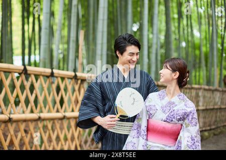 Coppia giapponese che indossa yukata per visitare il boschetto di bambù Foto Stock