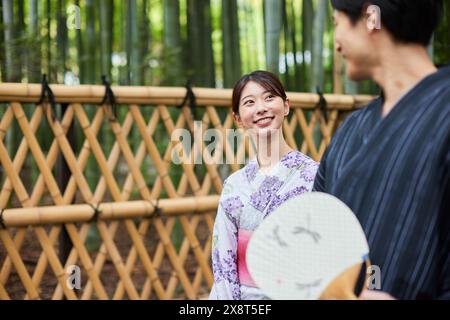 Coppia giapponese che indossa yukata per visitare il boschetto di bambù Foto Stock