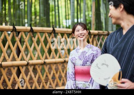 Coppia giapponese che indossa yukata per visitare il boschetto di bambù Foto Stock