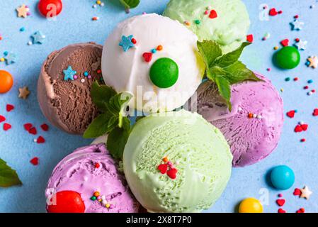 Vari cucchiai per gelato con spolverini di zucchero e foglie di menta da vicino. Yogurt biologico congelato nel deserto estivo. Foto Stock