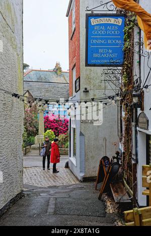 Due turisti nella stretta Cliff Street con l'ingresso al Fountain Inn, Mevagissey Cornwall Inghilterra Regno Unito Foto Stock