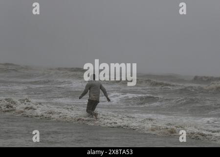 Patuakhali, Bangladesh. 27 maggio 2024. Un uomo cammina lungo la spiaggia durante le piogge dopo l'approdo del ciclone Remal a Kuakata. I residenti delle basse zone costiere del Bangladesh e dell'India hanno esaminato i danni il 27 maggio, quando un intenso ciclone si è indebolito in una tempesta pesante, con almeno due persone morte, tetti strappati e alberi sradicati. Credito: SOPA Images Limited/Alamy Live News Foto Stock