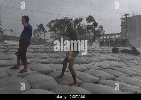 Patuakhali, Bangladesh. 27 maggio 2024. Uomini che lavorano nel vento pesante durante l'atterraggio del ciclone Remal a Kuakata. I residenti delle basse zone costiere del Bangladesh e dell'India hanno esaminato i danni il 27 maggio, quando un intenso ciclone si è indebolito in una tempesta pesante, con almeno due persone morte, tetti strappati e alberi sradicati. Credito: SOPA Images Limited/Alamy Live News Foto Stock