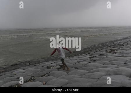 Patuakhali, Bangladesh. 27 maggio 2024. Un uomo che lavora nel vento pesante durante l'atterraggio del ciclone Remal, in una spiaggia a Kuakata. I residenti delle basse zone costiere del Bangladesh e dell'India hanno esaminato i danni il 27 maggio, quando un intenso ciclone si è indebolito in una tempesta pesante, con almeno due persone morte, tetti strappati e alberi sradicati. Credito: SOPA Images Limited/Alamy Live News Foto Stock