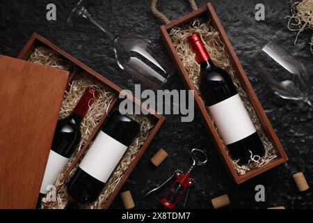 Composizione piatta con bottiglie di vino in scatole di legno su un tavolo a trama scura Foto Stock