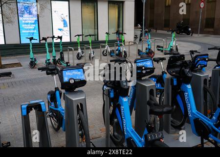 Madrid, Spagna. 13 febbraio 2024 - noleggio di biciclette da città e scooter elettrici parcheggiati sul marciapiede. Foto Stock