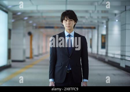 Uomo giapponese in tuta in piedi in un corridoio vuoto Foto Stock