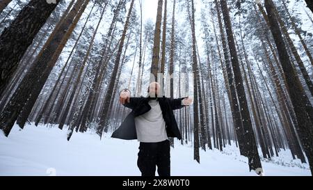 Ritratto di un bel giovane barbuto in abiti caldi in piedi all'aperto nel parco il giorno invernale. Supporto. Modello biondo hipster nei legni. Foto Stock