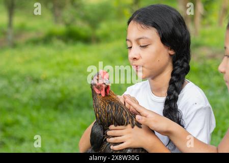 primo piano di una ragazza latina che tiene in mano un pollo mentre lo guarda e lo tocca. Foto Stock