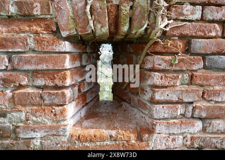Finestra con fessure a freccia nel vecchio muro di mattoni del castello Foto Stock